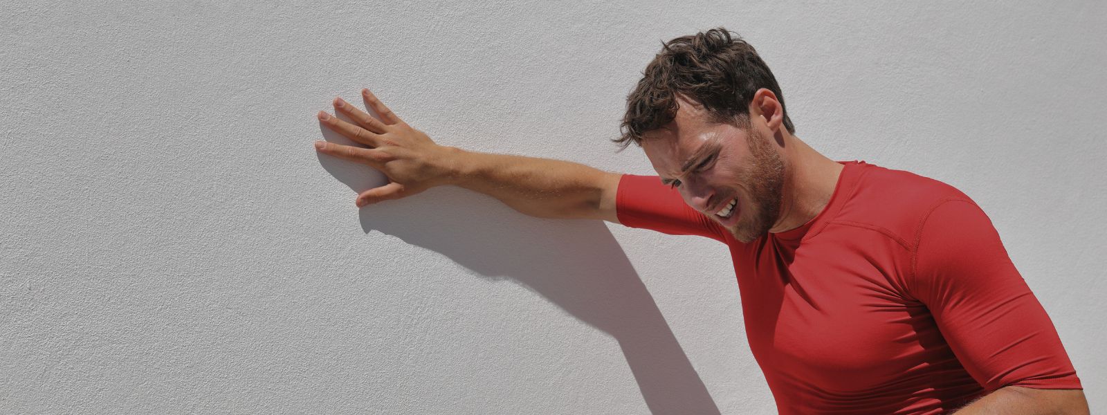 man with hand on wall taking a breather after exercise